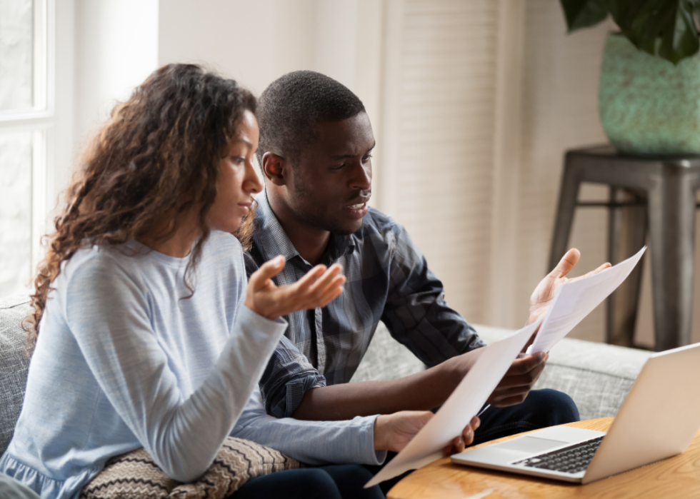 Two people with paperwork in front of a laptop.
