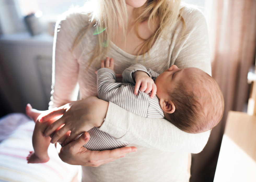 Unrecognizable young mother holding a baby in her arms.