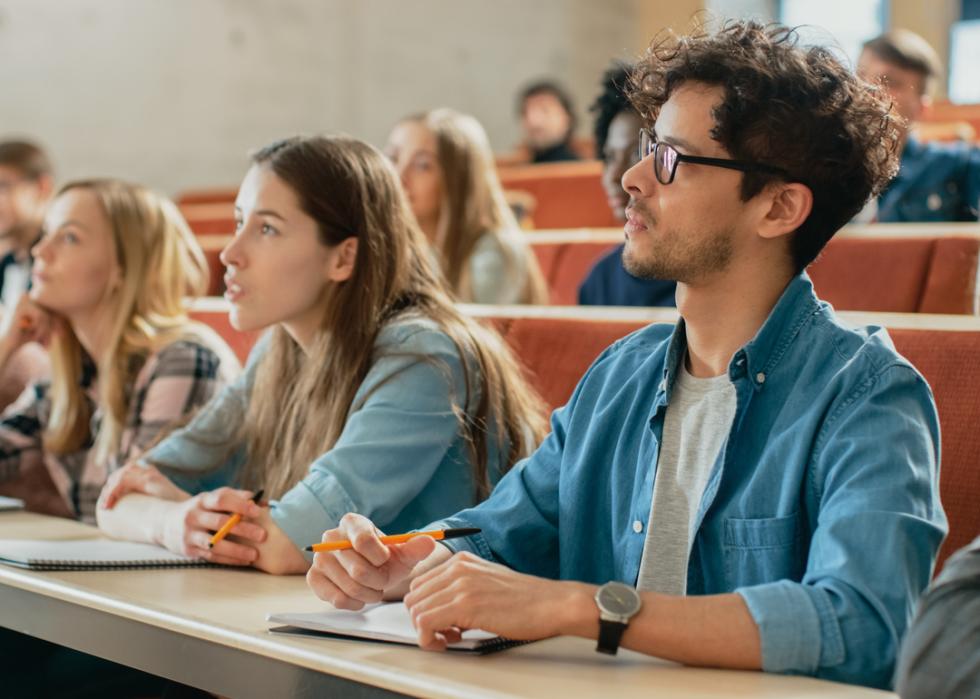 Students listening to a lecturer in class and taking notes