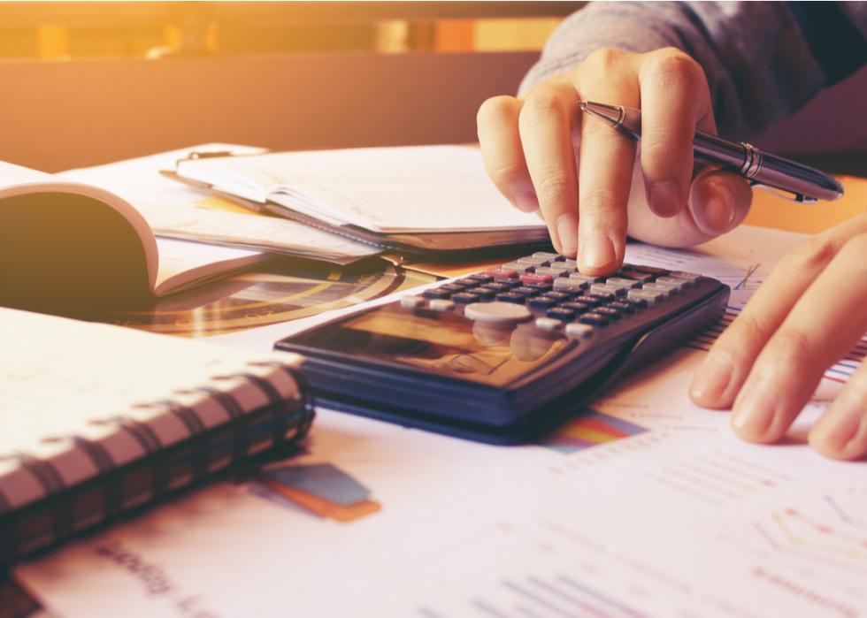 A woman using a calculator while managing her finances at her home office