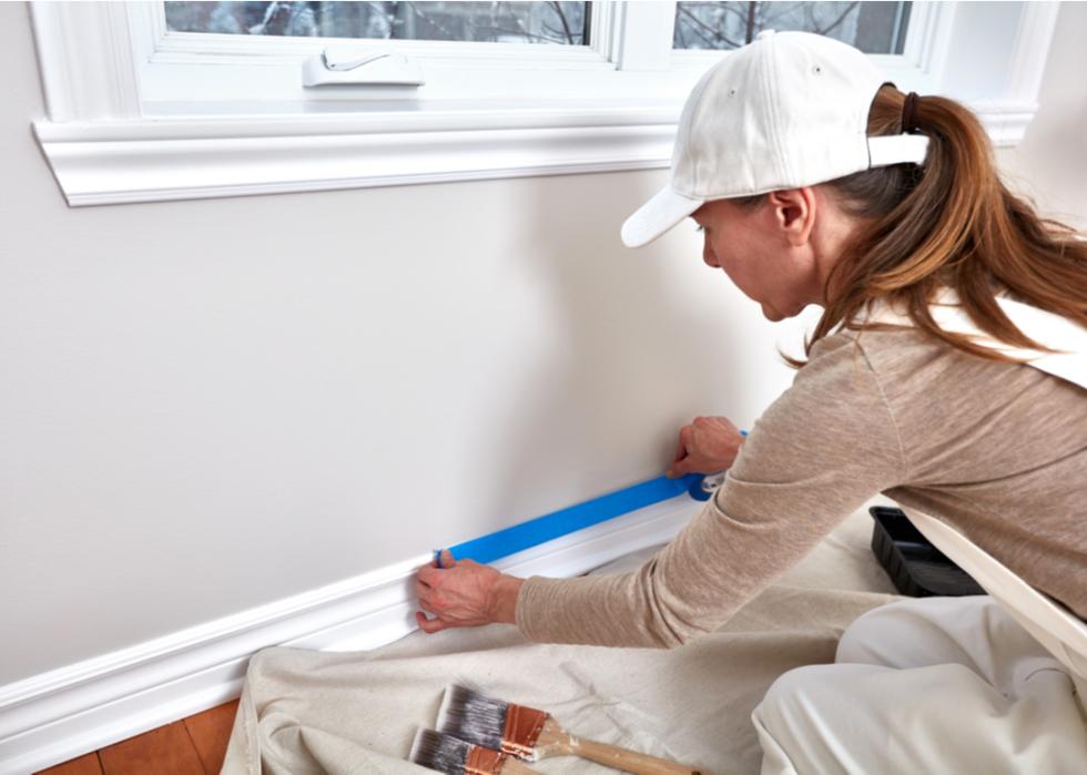 A woman painting a wall inside a home