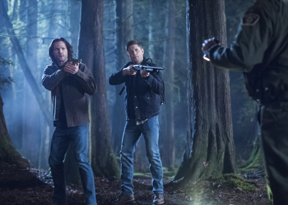 Jensen Ackles, Adam Beach, and Jared Padalecki in a standoff in the woods.