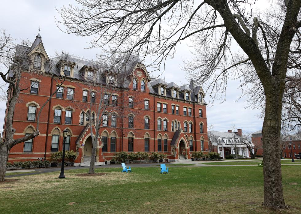 A building on the Tufts University campus with two electric blue Adirondack chairs in front of it.