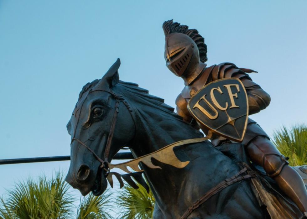 A statue of a knight holding a UCF shield on a horse.