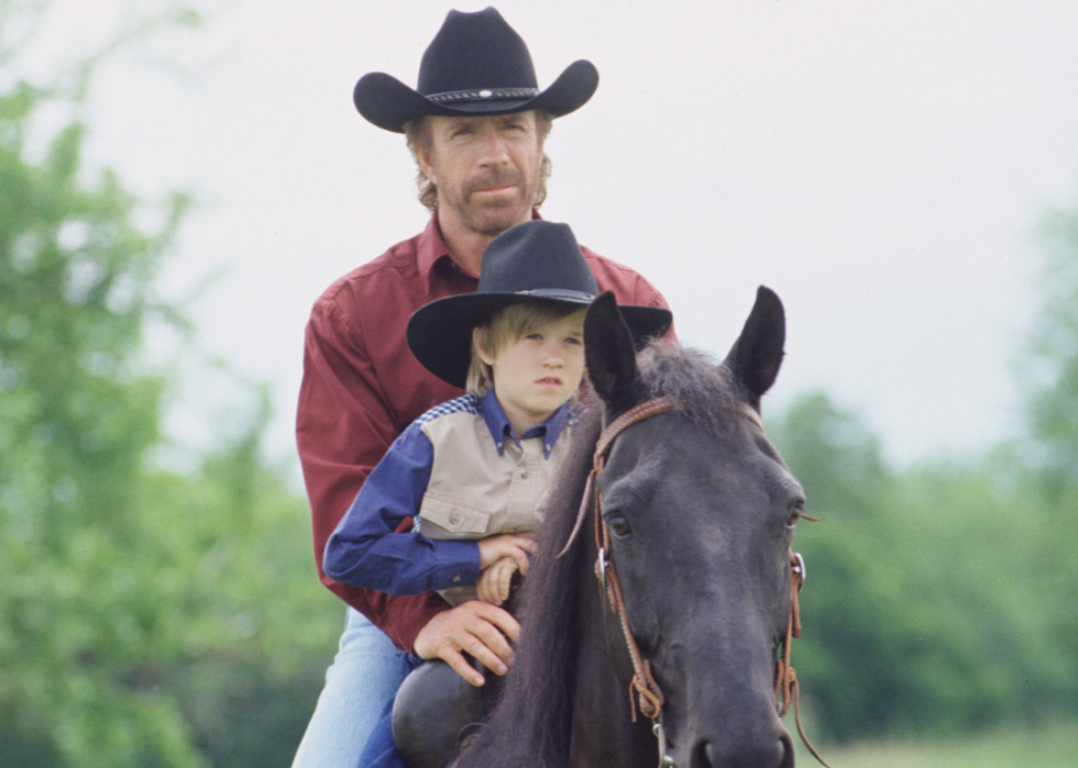 Chuck Norris and Haley Joel Osment riding a horse.