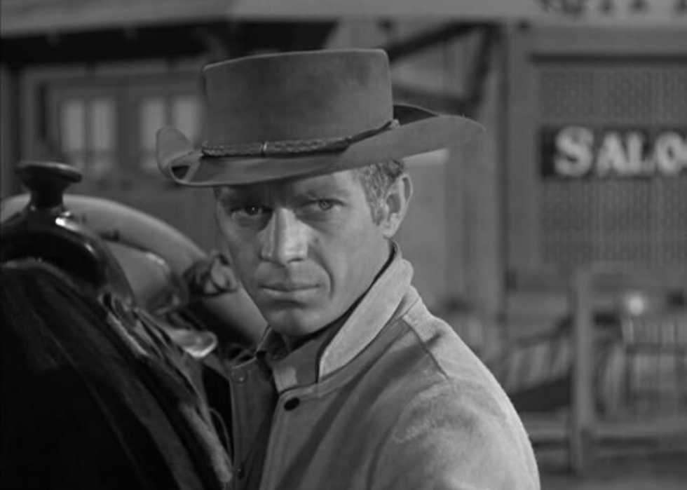 A cowboy next to a horse.