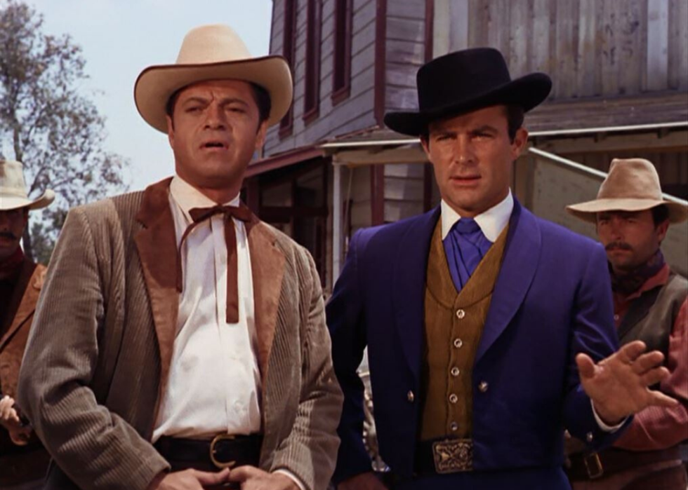 A man in a blue western suit and another in a corduroy jacket.