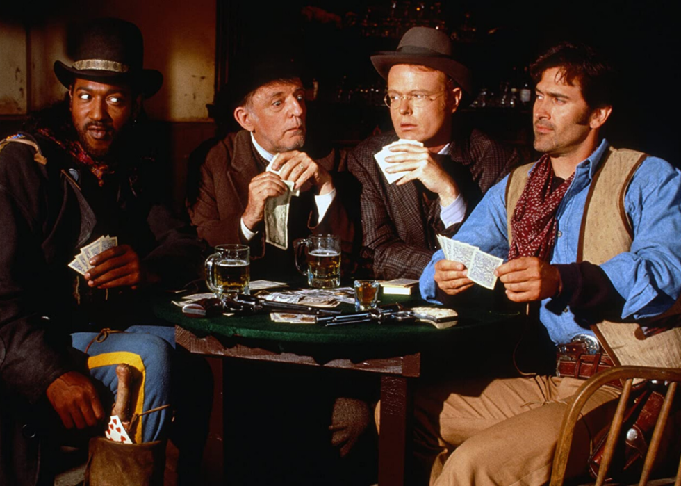 Four cowboys making funny faces during a card game.