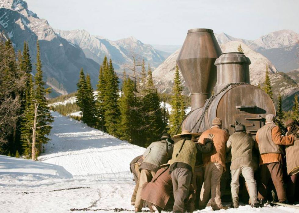 A group of people pushing a train car in the snow.