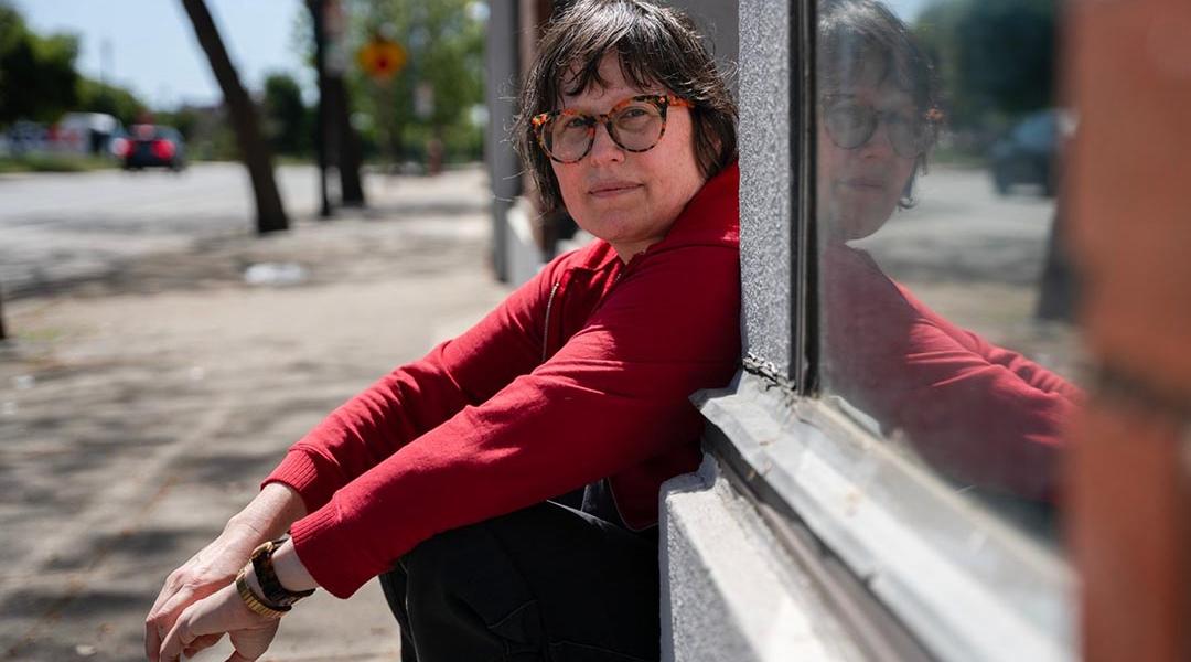 Julie Crossman sitting on a stoop wearing a red long-sleeve shirt, is the sister of Nanie Crossman who she lost touch with, in Oakland on April 8, 2025