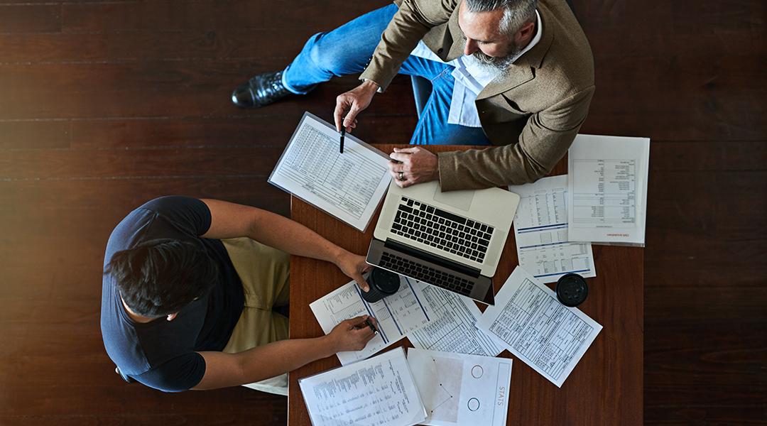 Two businessmen discussing strategy with accounting documents on their table.