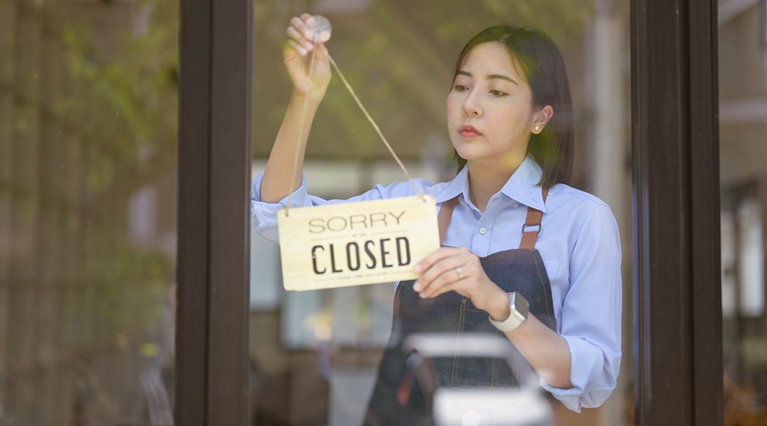 Small business owner changes store sign to closed.