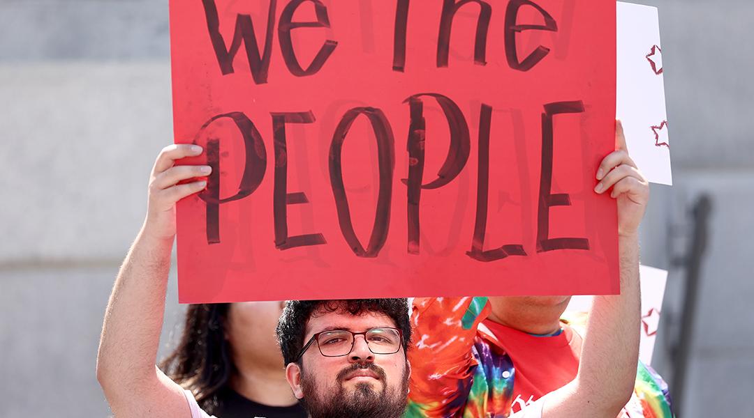 Demonstrators hold signs during the We The People March in Los Angeles, California.