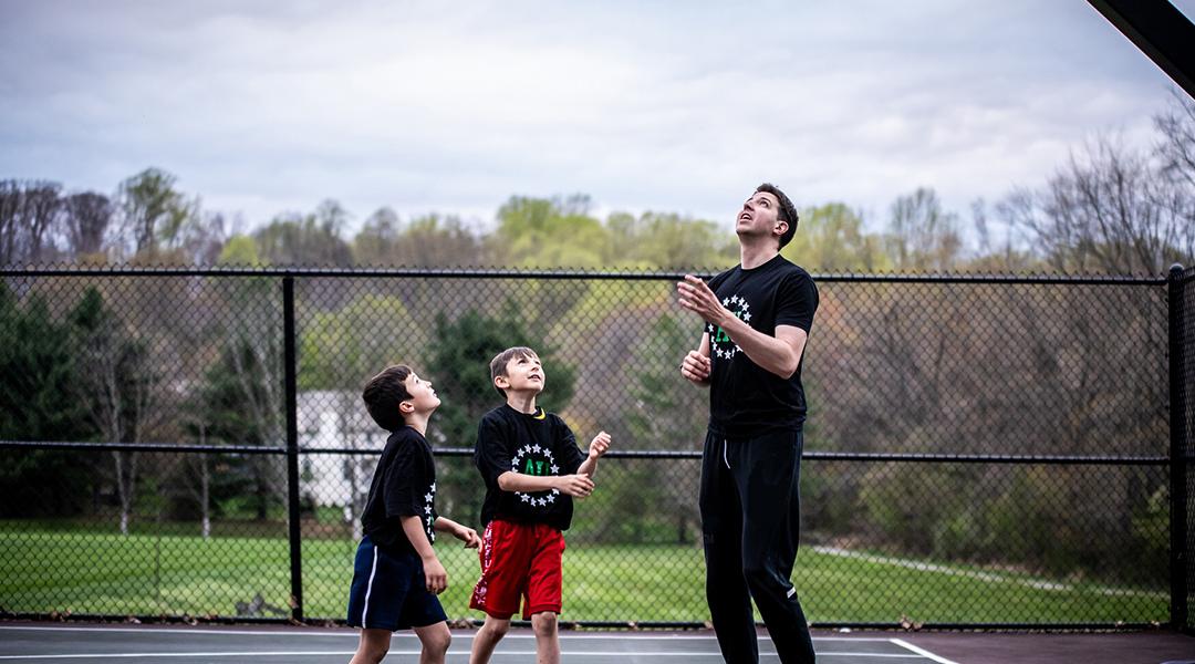 A private sports coach in a basketball session with two young boys.
