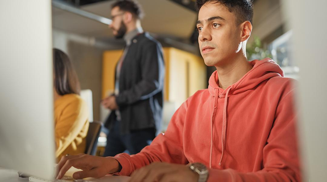 A male student using a desktop computer for application tasks.