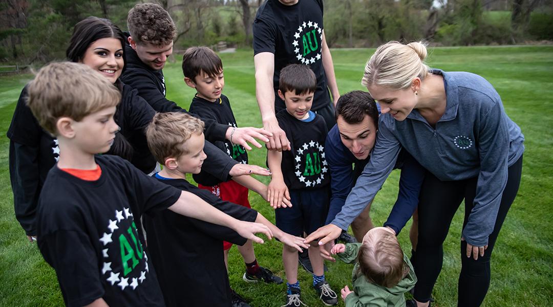 A group of young kinds with their parents form a circle to join hands before a game.