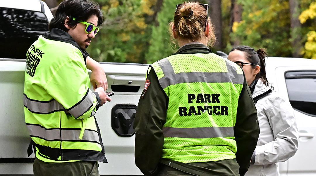 Three park rangers behind their car on duty at Curry Village in the Yosemite Valley at Yosemite National Park, California.