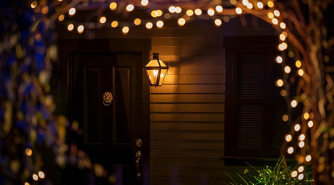 Holiday lights during night designed around an arch leading to a house's doorway.