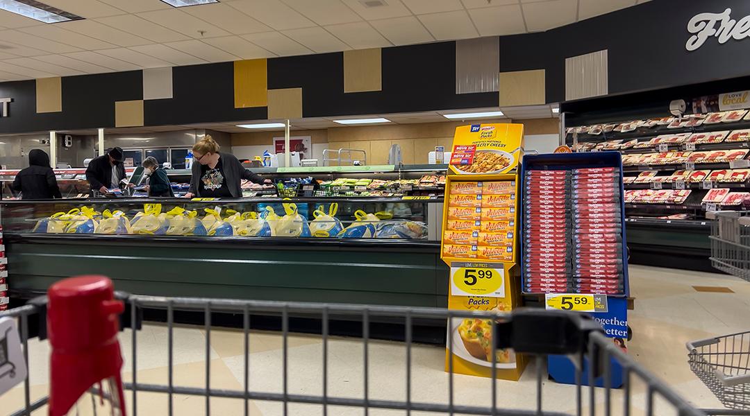 Wide view of people shopping for Butterball Thanksgiving turkeys inside a grocery store.