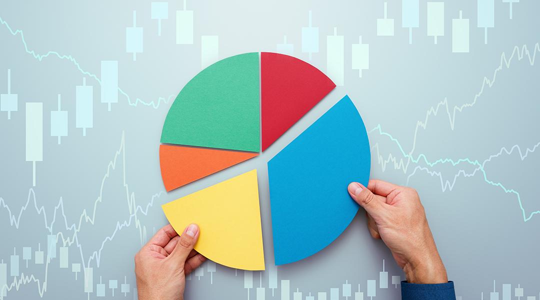 A person completing a pie chart with candlestick, investment charts graphics.