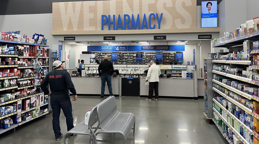 Customers picking up items at a pharmacy counter.