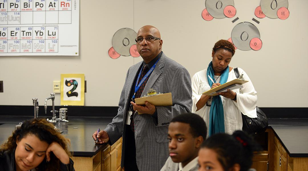 Godfrey Rangasammy, Supervisor of Science, background center, and Tanisha Johnson, a Science Coach, right, background, observe a chemistry class as Literacy coaches at Northwestern High School in Hyattsville, Maryland.
