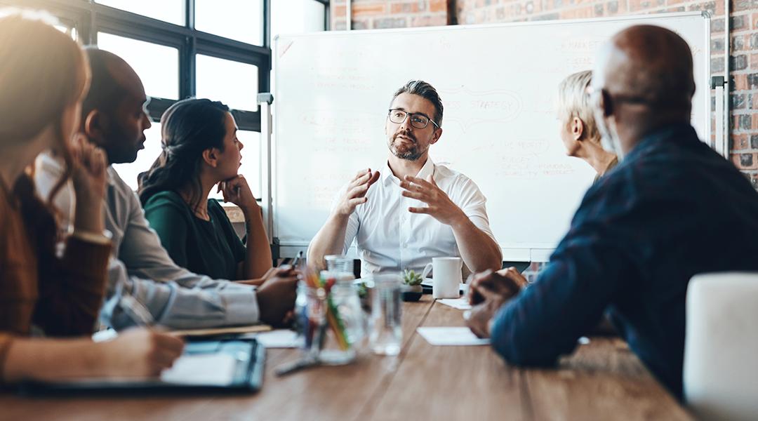 A manager leading a team meeting in a boardroom.