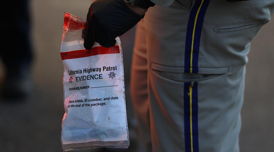 A California Highway Patrol officer holding an evidence bag after taking a suspect into custody.