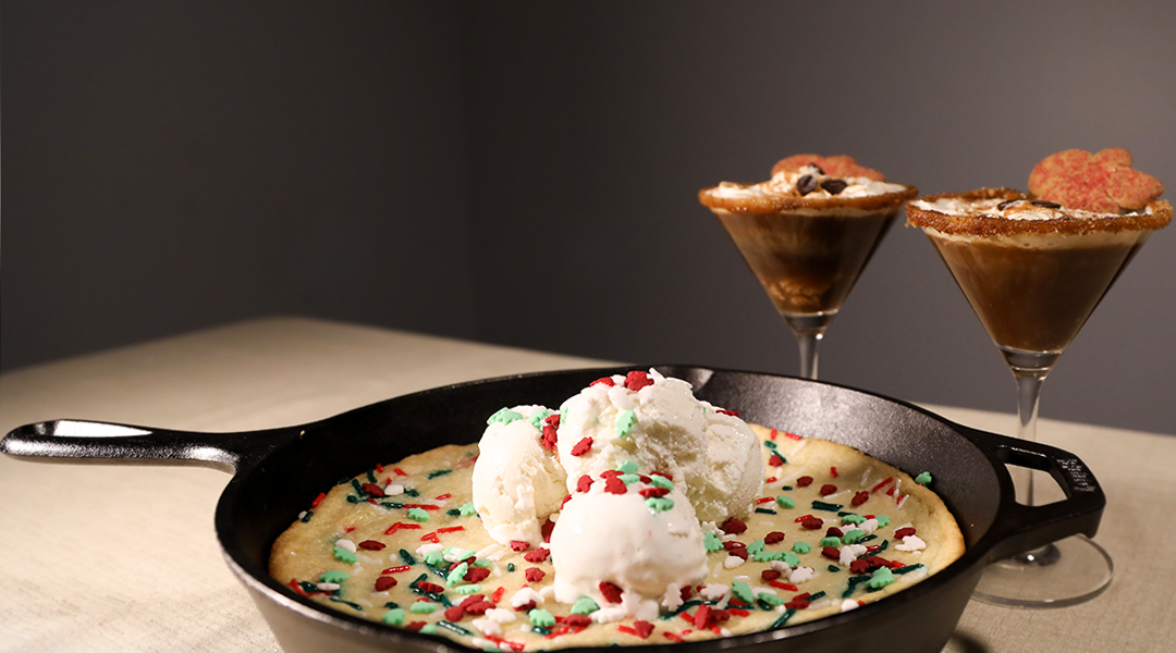 A 'Winter Wonderland' sugar cookie on a skillet with two glasses of gingerbread espresso martini.
