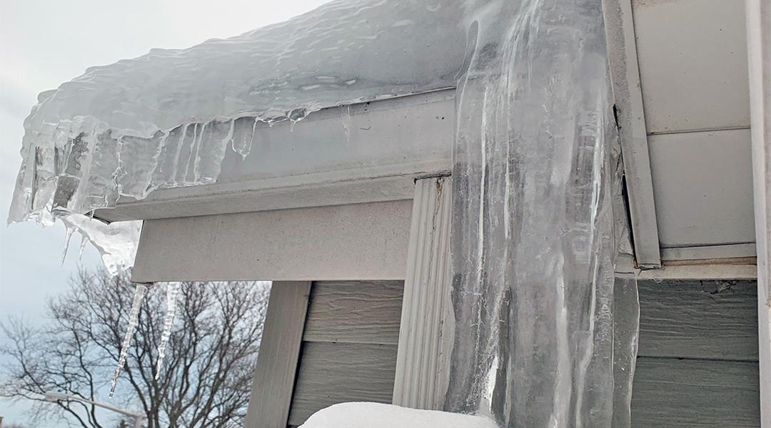 Thick ice dam formed on a house's roof.