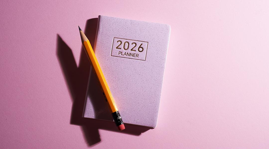 A pink 2026 planner with a pencil against a pink background.